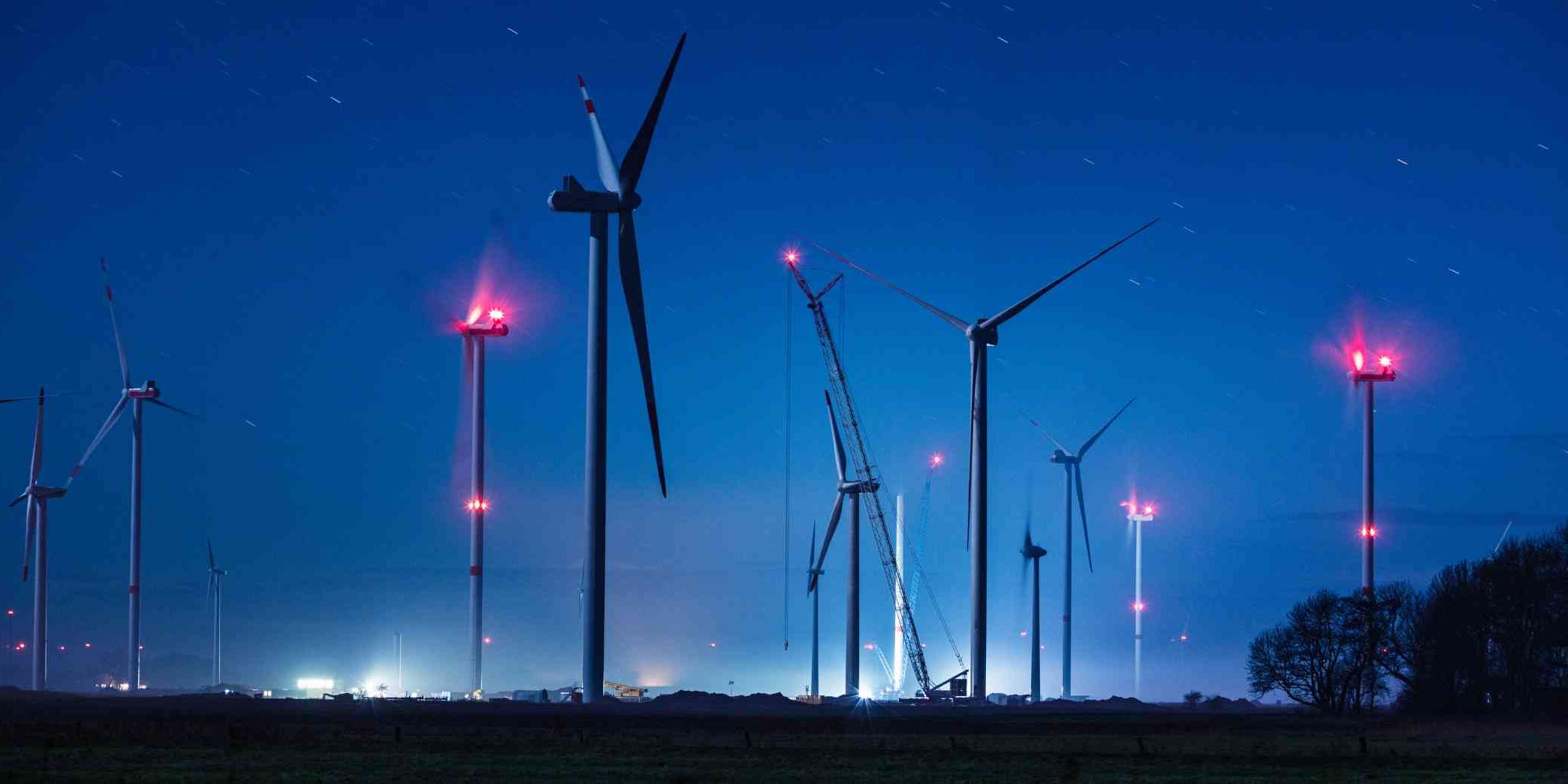 Windpark bei Nacht mit leuchtenden roten Hindernisfeuern