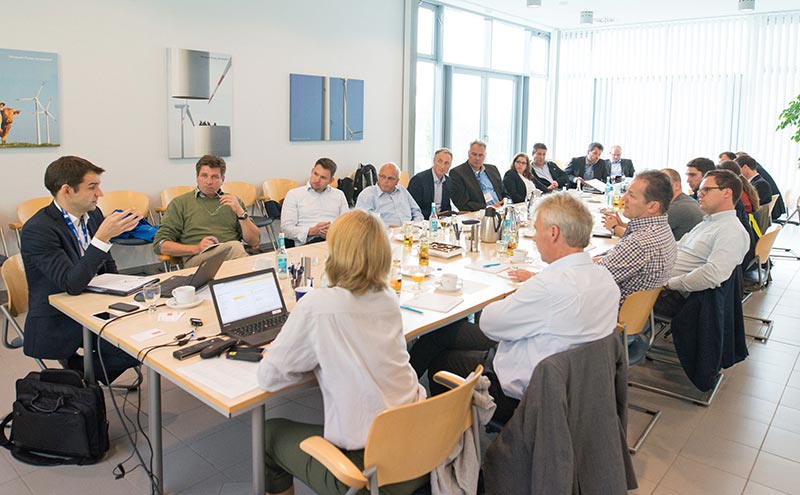 Viele Menschen sitzen an einem großen Tisch und diskutieren